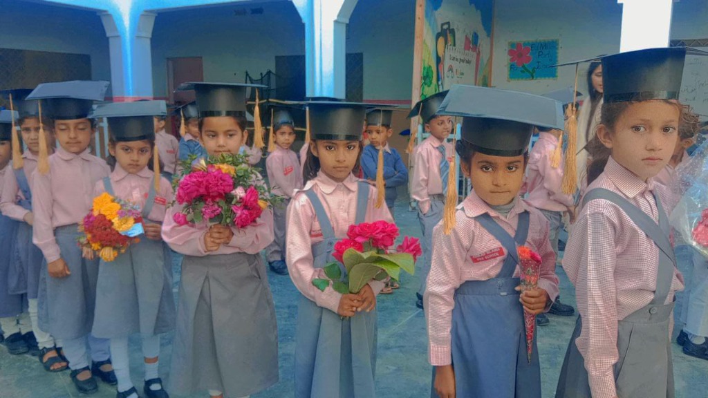 Young students in graduation caps and uniform holding flowers